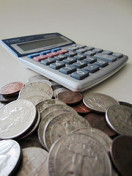 Small Calculator Next To Pile Of Coins