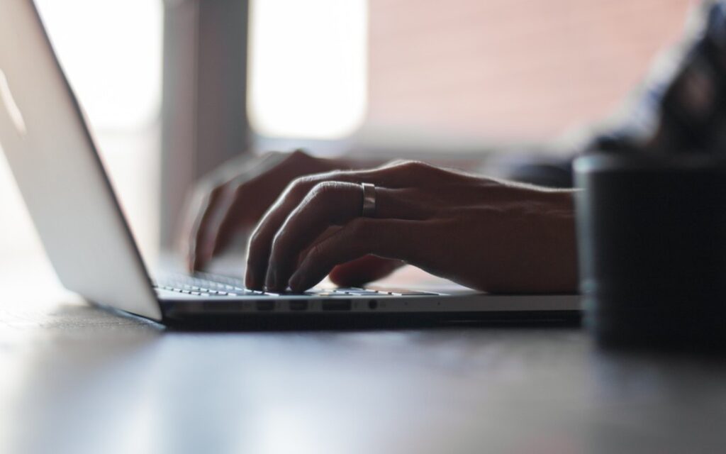 Hands typing on a laptop